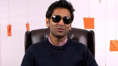 Image of man wearing dark glasses, surrounded by orange envelopes