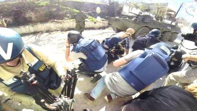 Journalists taking cover from explosions behind a tank in Latakia, Syria