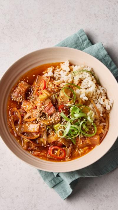Top down view of a stew with rice in a pink bowl.