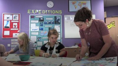 Pupils and teacher drawing at a desk