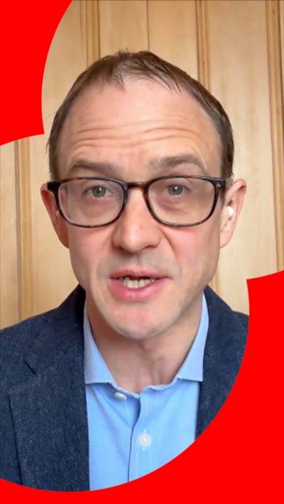 Chris Mason looks straight at the camera. He wears black-rimmed glasses and blue blazer and shirt.