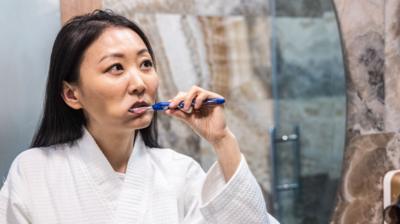 Woman facing a mirror and brushing her teeth