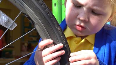 Litte girl checking puncture on a tyre.