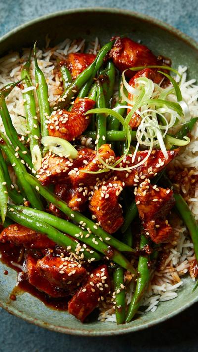 Top down view of a green bowl with chicken and green beans in