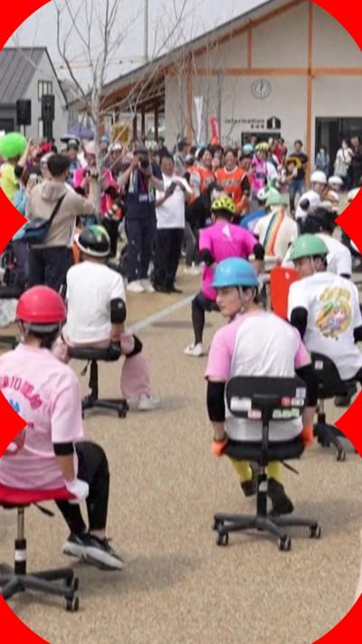 People sitting in office chairs, outside, wearing hard hats