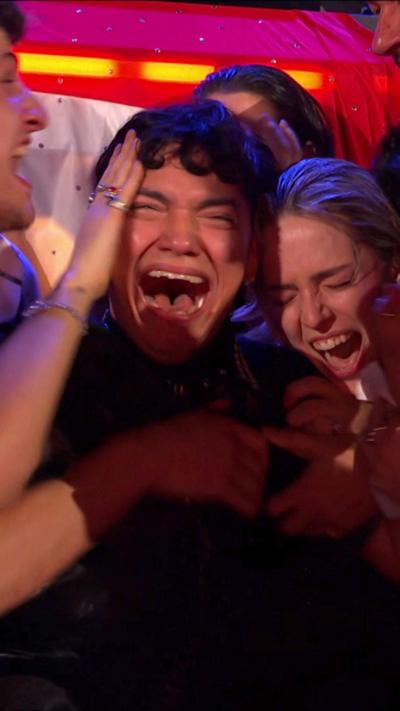 JJ clutches his head as he is surrounded by people