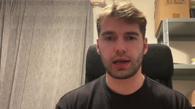 A man sitting in a room on a chair looking directly at the camera. He is being interviewed on TV about being an eyewitness to the attack