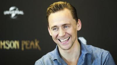 Tom Hiddleston happily grins for the cameras promoting his current film, a gothic horror called Crimson Peak