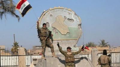 A member of the Iraqi security forces holds an Iraqi flag in the city of Ramadi