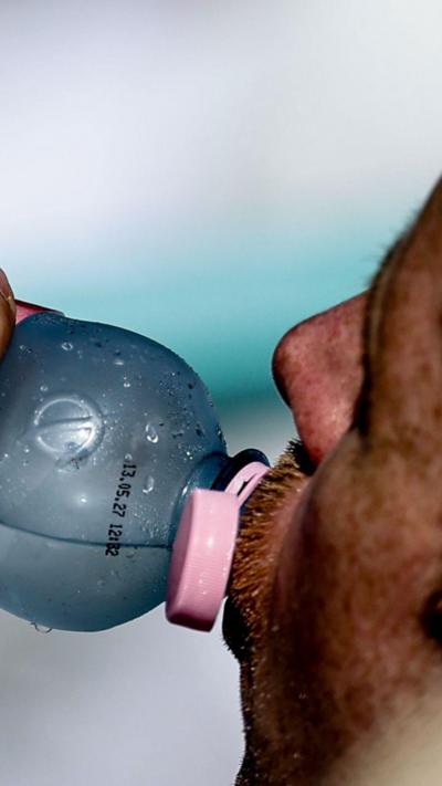 A close up shot of a man drinking a bottle of water