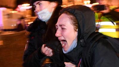 A protester is held by police officers at an anti-war demonstration in Moscow