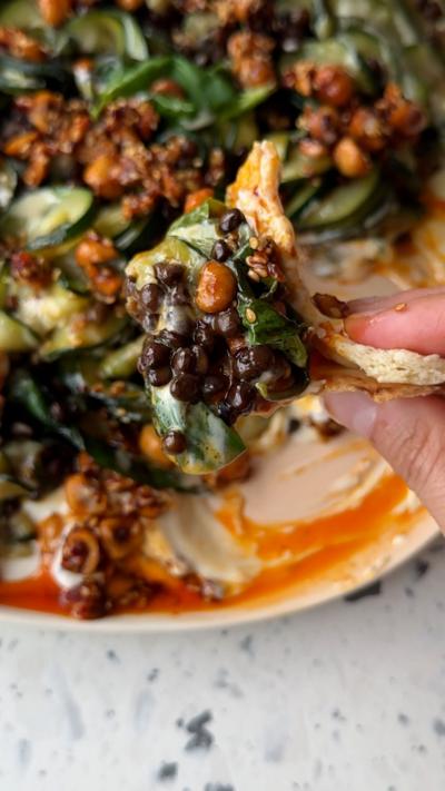 Caramelised courgettes being scooped out of a bowl on a piece of flatbread.
