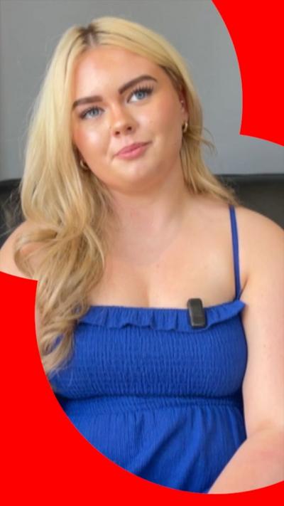 A young woman with blonde hair is sitting with her head tilted to one side. She is wearing a blue summer dress.