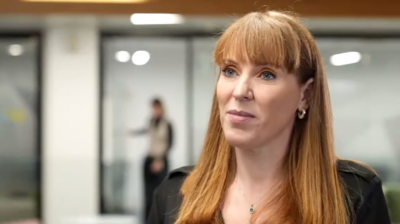 Angela Rayner standing in an office setting, wearing a black top, being interviewed by the BBC