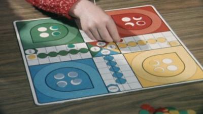 Image of a hand moving a counter around a board game