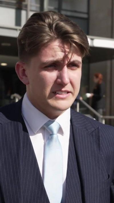 A man with brown hair in a blue suit and waistcoat with white shirt and pale blue tie