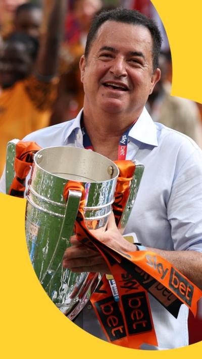 A man with short dark hair holding a silver trophy.