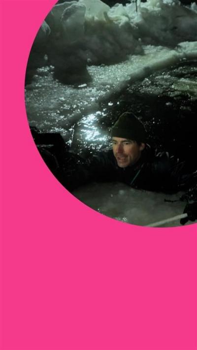 Simon Reeve in a pool of icy water at night time
