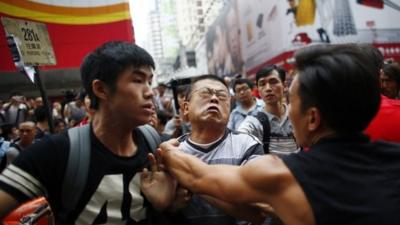 An anti-Occupy Central protester (C) scuffles with pro-democracy protesters as he tries to remove a barricade at a main street at Hong Kongs Mongkok shopping district October 4, 2014