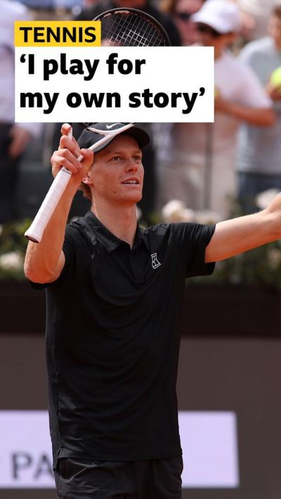 Jannik Sinner celebrating a win at the Italian Open. He is wearing a black shirt and holding a tennis racquet.
