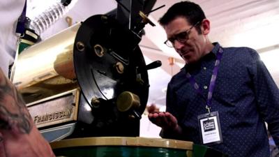 Man examining coffee beans in a roaster