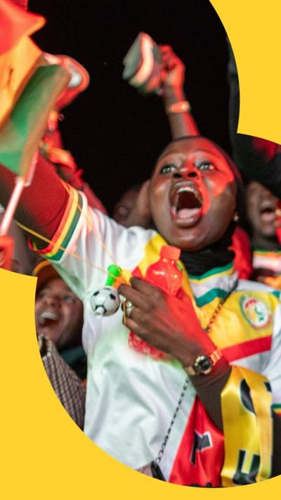 A woman celebrates amongst a crowd of football fans in Dakar, Senegal