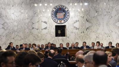 Former FBI Director James Comey (back to camera) testifies before the US Senate Select Committee on Intelligence hearing