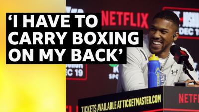 'I have to carry boxing on my back' text quote over Anthony Joshua speaking a news conference