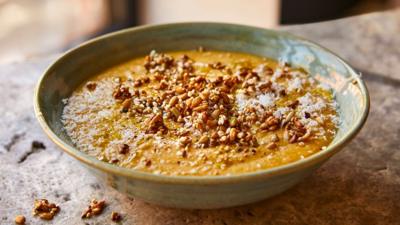 A green bowl with thick soup in and seeds sprinkled on top.