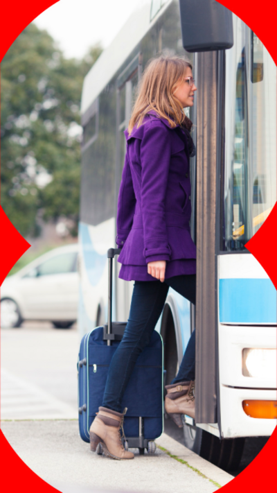 A woman in a purple coat, with a suitcase getting on a bus