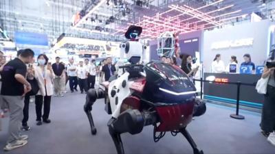 A humanoid robot riding a mechanical horse in front of onlookers