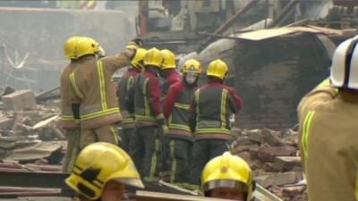 Firemen survey the wreckage of the flour mill