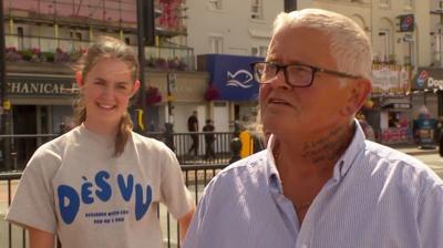 A young woman and an older man squint in the sun on the Margate streets