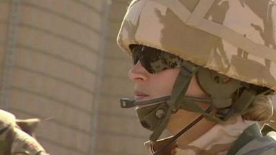 Photo of female soldier in uniform, her face covered by helmet and goggles