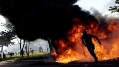 Demonstrator runs near a burning barricade