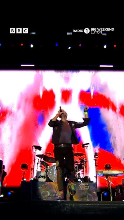 Coldplay at Radio 1 Big Weekend festival. The stage is lit up with colour.