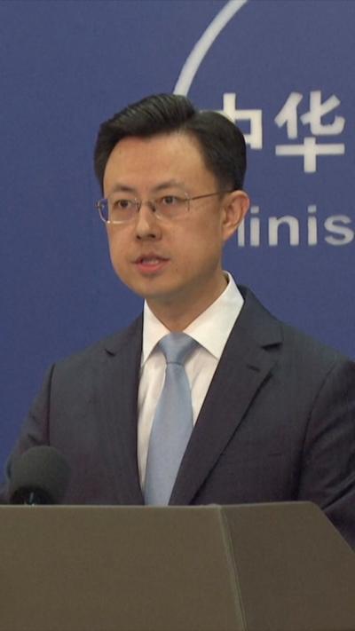 Chinese government spokesperson in a blue suit behind a podium