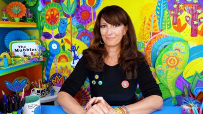 author liz pichon infront of a bright multicoloured doodle wall