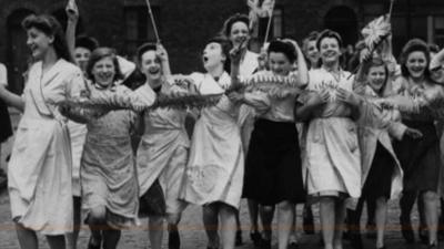 Women dance jubilantly waving Union flags 