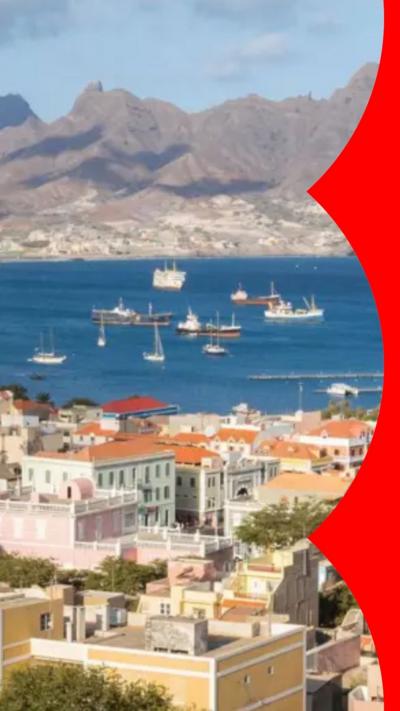 The Cape Verde skyline showing mountains in the background with the blue ocean in front and many colourful homes in the foreground.