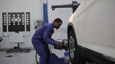 A factory worker assembles a car in Rwanda