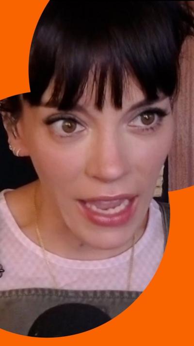 Lily Allen looks shocked - she has a brown fringe and wears a pink top 