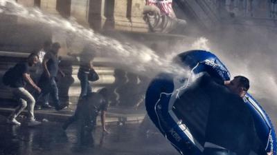 Protester uses inflatable boat to shield himself from water cannon in Rome