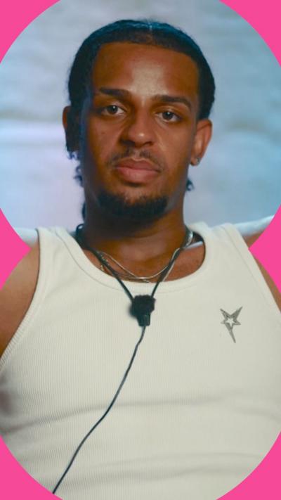 A man wearing a white vest looks straight down the camera 