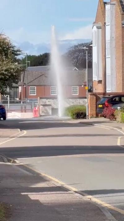 Jet of water sprays into air in middle of residential street