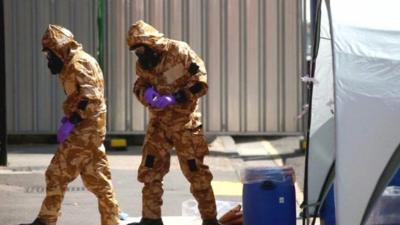 Investigators in hazardous material suits enter building