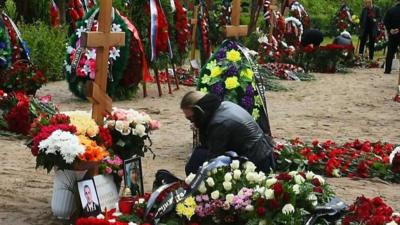 A woman kneels by the grave of one of the soldiers