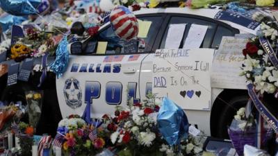 Notes, flowers and other items decorate a squad car at a make-shift memorial in front of the Dallas police department - July 9, 2016