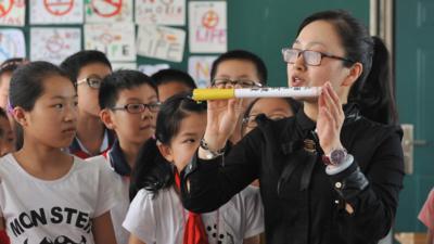 A woman holds up a large cigarette during an anti-smoking seminar in China