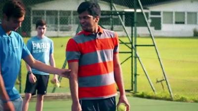 A volunteer helping at a blind tennis session